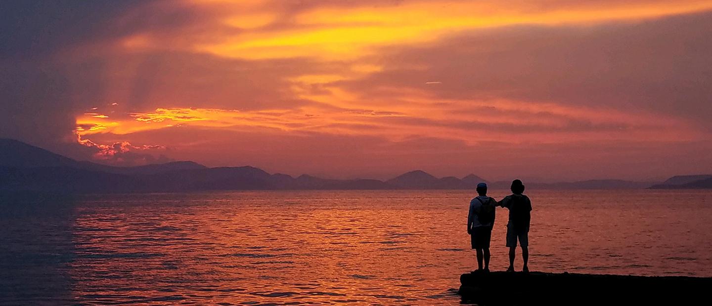 两个人在一大片水域上面对日落的画面